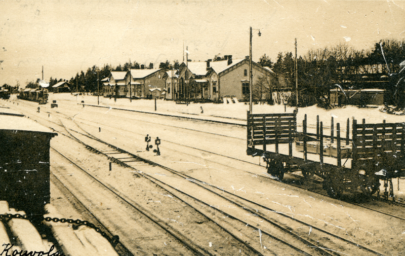 Luminen ratapiha, jonka raiteilla seisoo vaunuja. Asemarakennuksen edessä on asemalaituri ja taustalla puita ja muita rakennuksia.